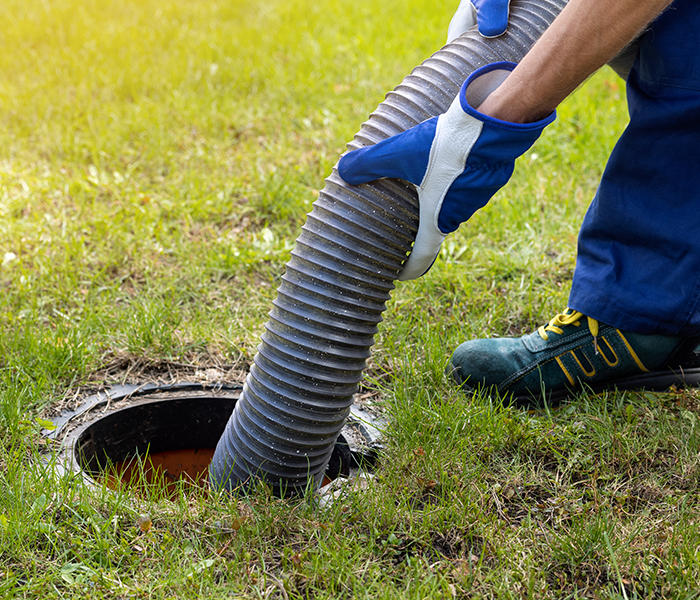 man holding hose to clean out septic